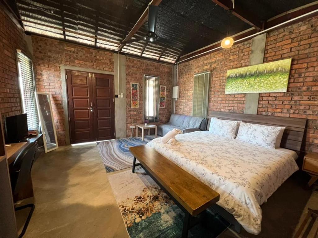 een slaapkamer met een groot bed en een bakstenen muur bij Rembulan Escape - The Red Bowl in Kampung Penarik