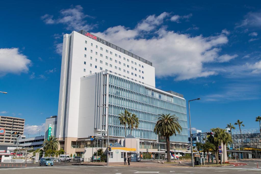 een groot wit gebouw met palmbomen ervoor bij JR Kyushu Hotel Miyazaki in Miyazaki