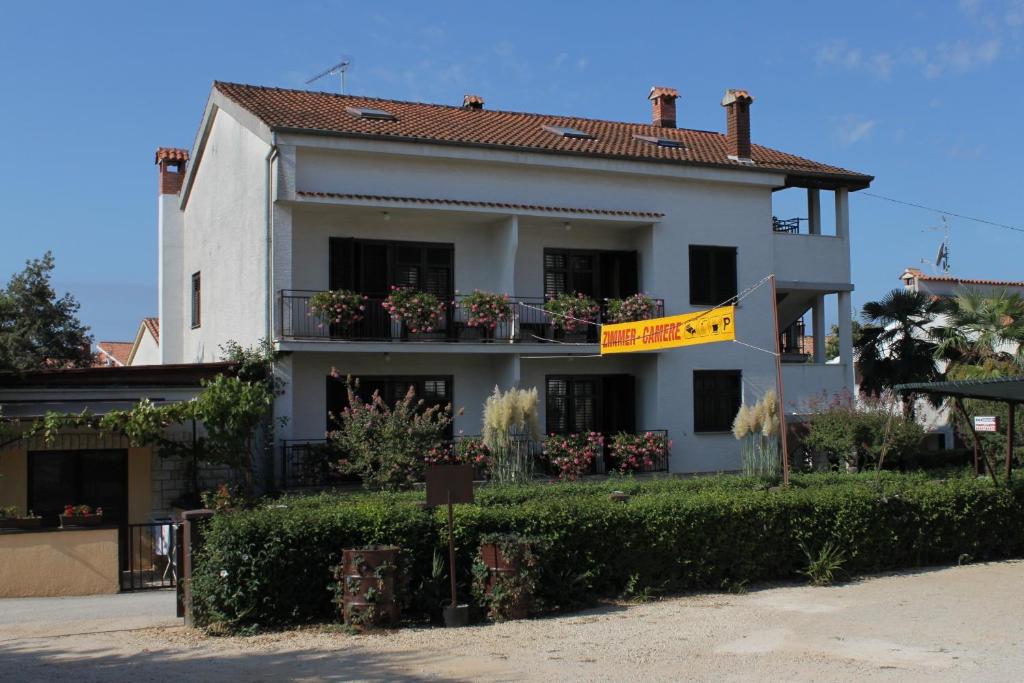 une maison blanche avec un drapeau jaune devant elle dans l'établissement Apartments and rooms with parking space Porec - 6917, à Poreč