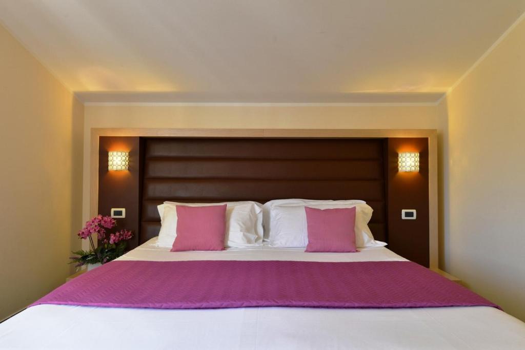 una camera da letto con un grande letto con cuscini rosa e bianchi di Hotel Rosignano a Rosignano Solvay