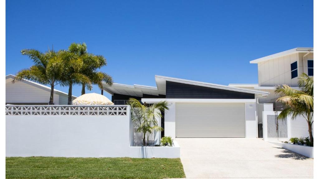a white house with palm trees and a garage at Fennes On Banzai in Kingscliff
