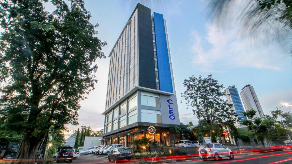 a tall building with cars parked in front of it at Cleo Hotel Jemursari Surabaya in Surabaya
