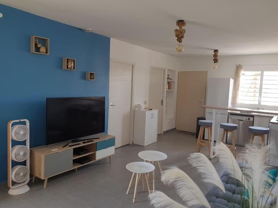 ein Wohnzimmer mit einem TV und einer blauen Wand in der Unterkunft Mangrov in Le Moule