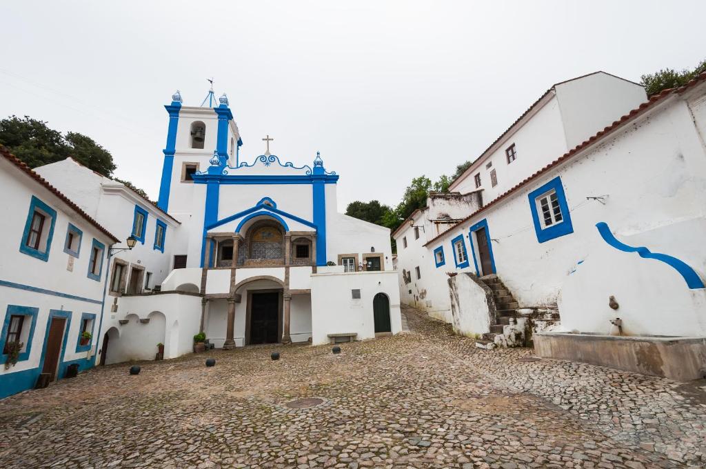 a group of white and blue buildings with a church at Casas De Romaria in Brotas