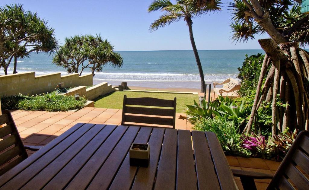 a wooden picnic table with a view of the beach at Beach at your feet in Bargara