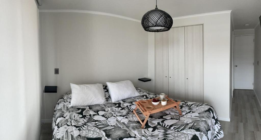 a bedroom with a bed with a table on it at Departamento Aqua La Serena in La Serena