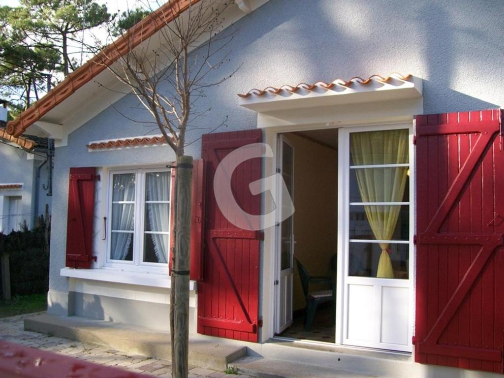 une maison avec des portes rouges et une fenêtre dans l'établissement Maison T3, 200m Plage Ste Anne, Animaux admis, Parking - FR-1-357-91, à La Tranche-sur-Mer