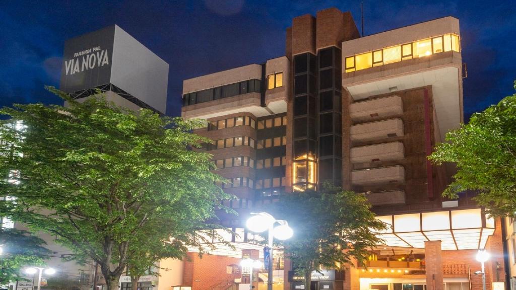 a building at night with trees in front of it at Hotel Global View Hachinohe in Hachinohe