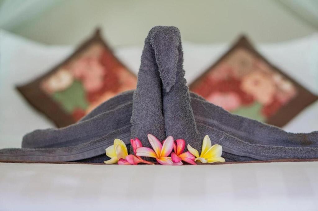 una pila de toallas púrpuras con flores en la parte superior en Bangbang Guest House Ubud, en Ubud