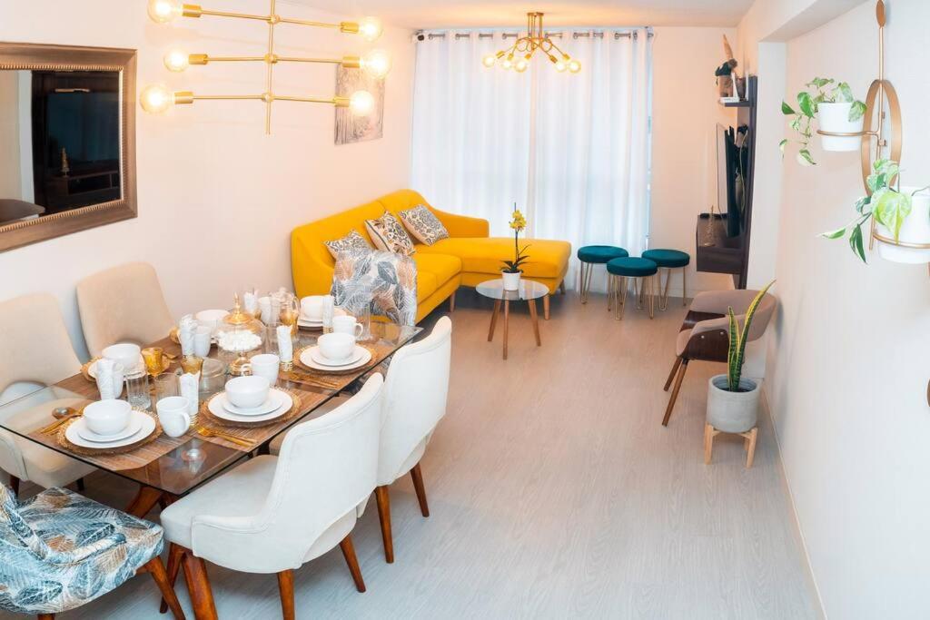 ein Wohnzimmer mit einem Tisch und einem gelben Sofa in der Unterkunft Hermoso departamento de estreno in Lima
