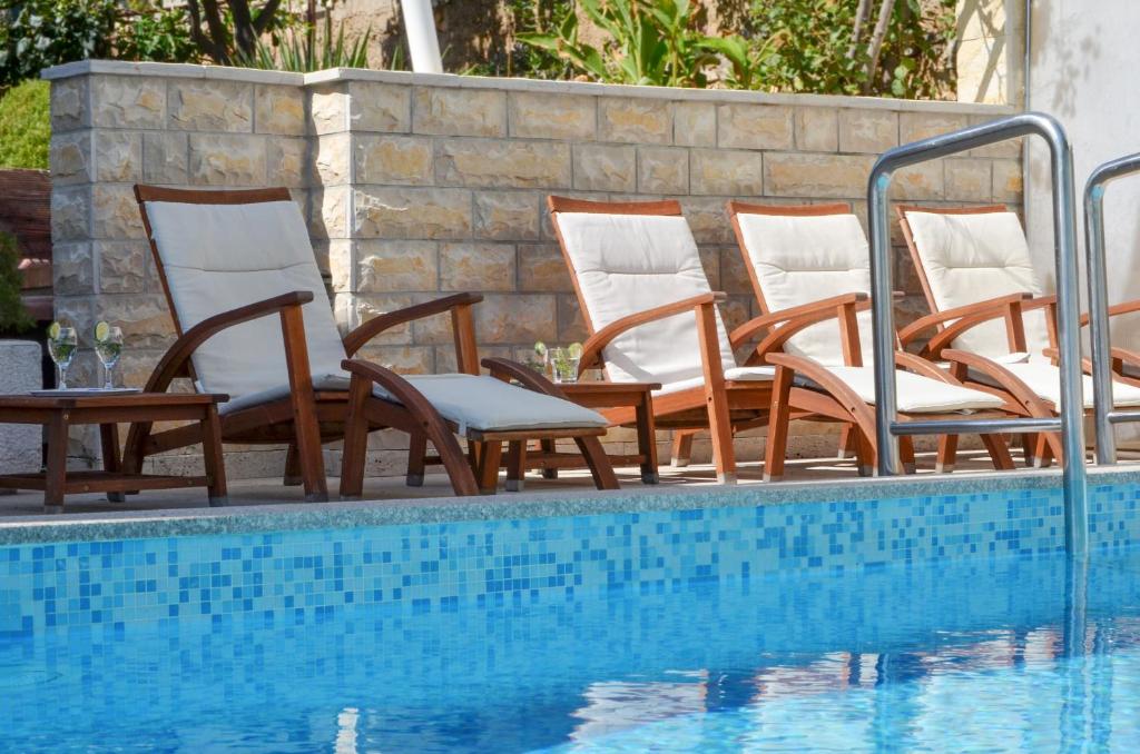 a group of chairs next to a swimming pool at Apartments Inge in Seget Vranjica