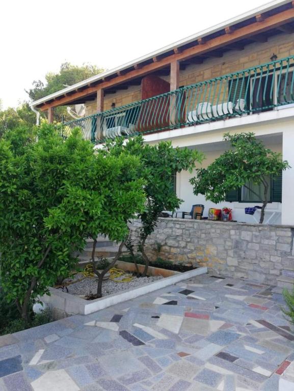 a building with a balcony and two trees in front of it at Apartments Rogac in Rogač