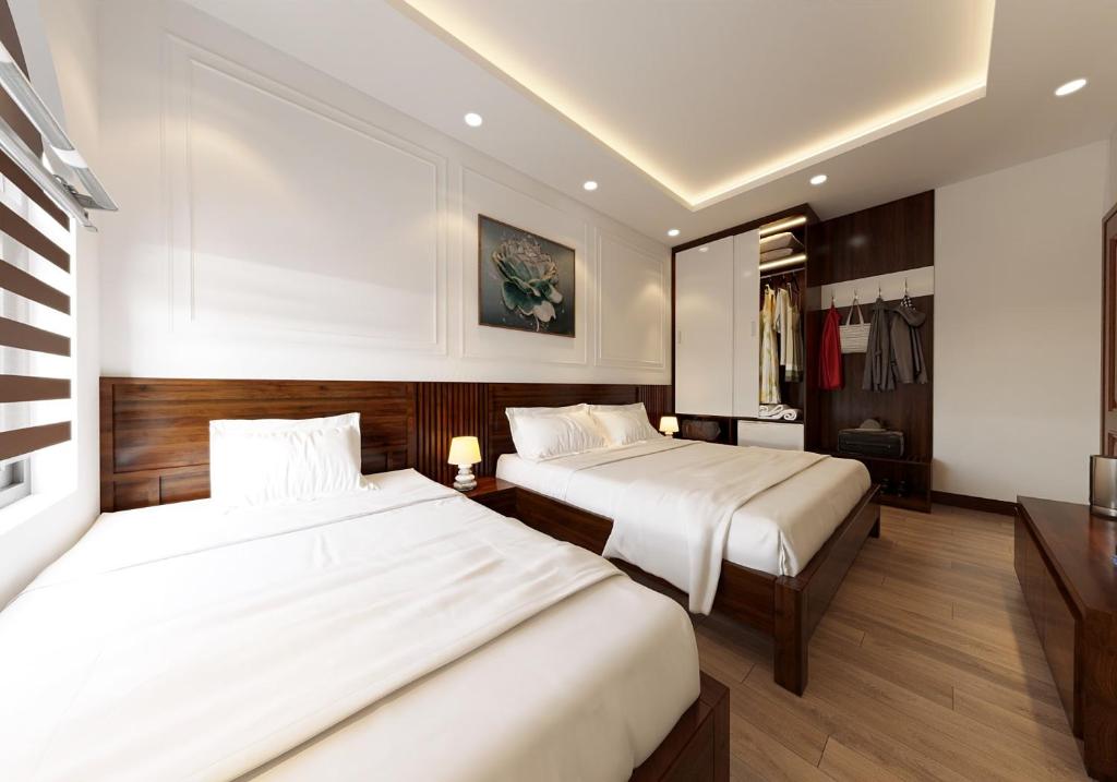 2 camas en una habitación de hotel con sábanas blancas en Tamcoc Catalina Hotel en Ninh Binh