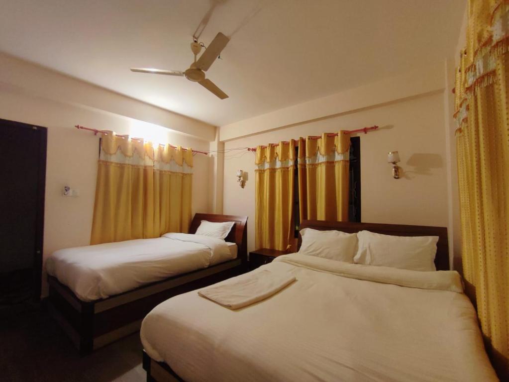 a hotel room with two beds and a ceiling fan at Hotel Town View in Sauraha