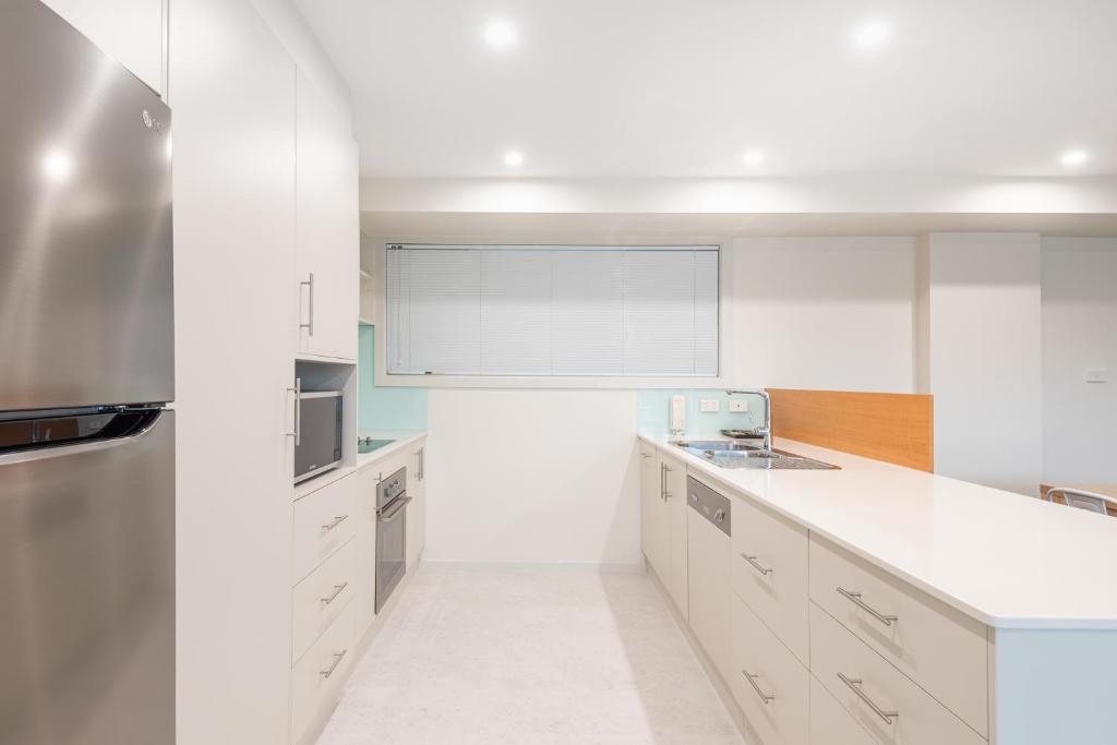 una cucina con armadi bianchi e piano di lavoro bianco di Warners Bay Apartments a Warners Bay