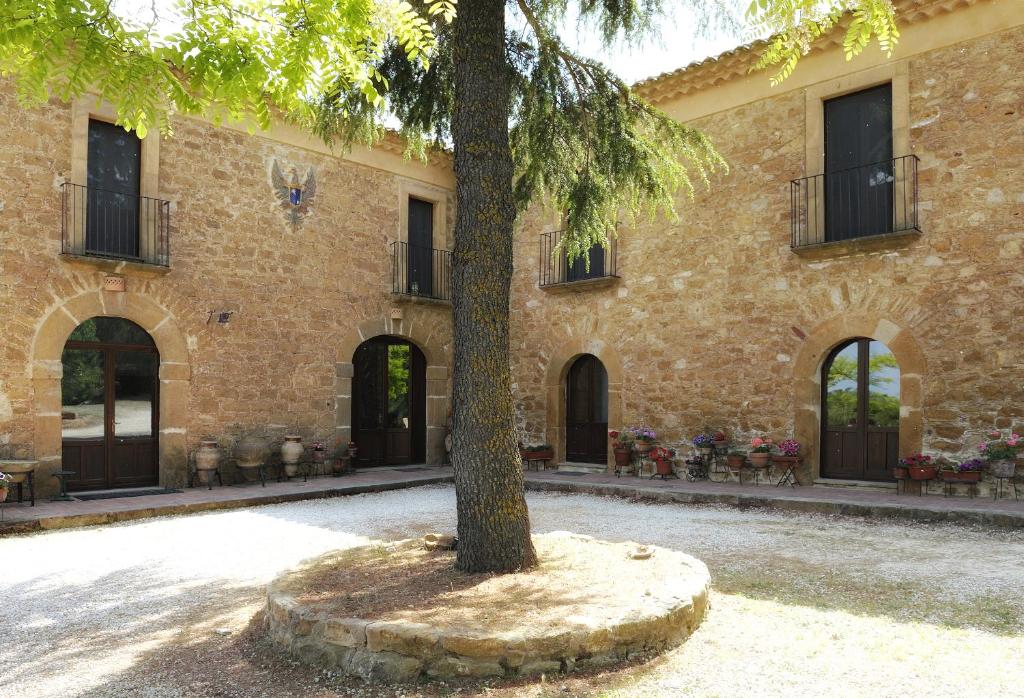 a tree in front of a building with a clock on it at Villa Trigona in Piazza Armerina
