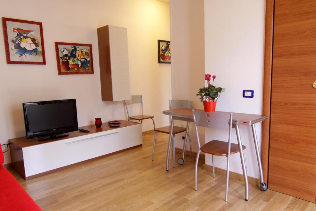 sala de estar con TV y mesa con sillas en Appartamenti Velez, en Pisa