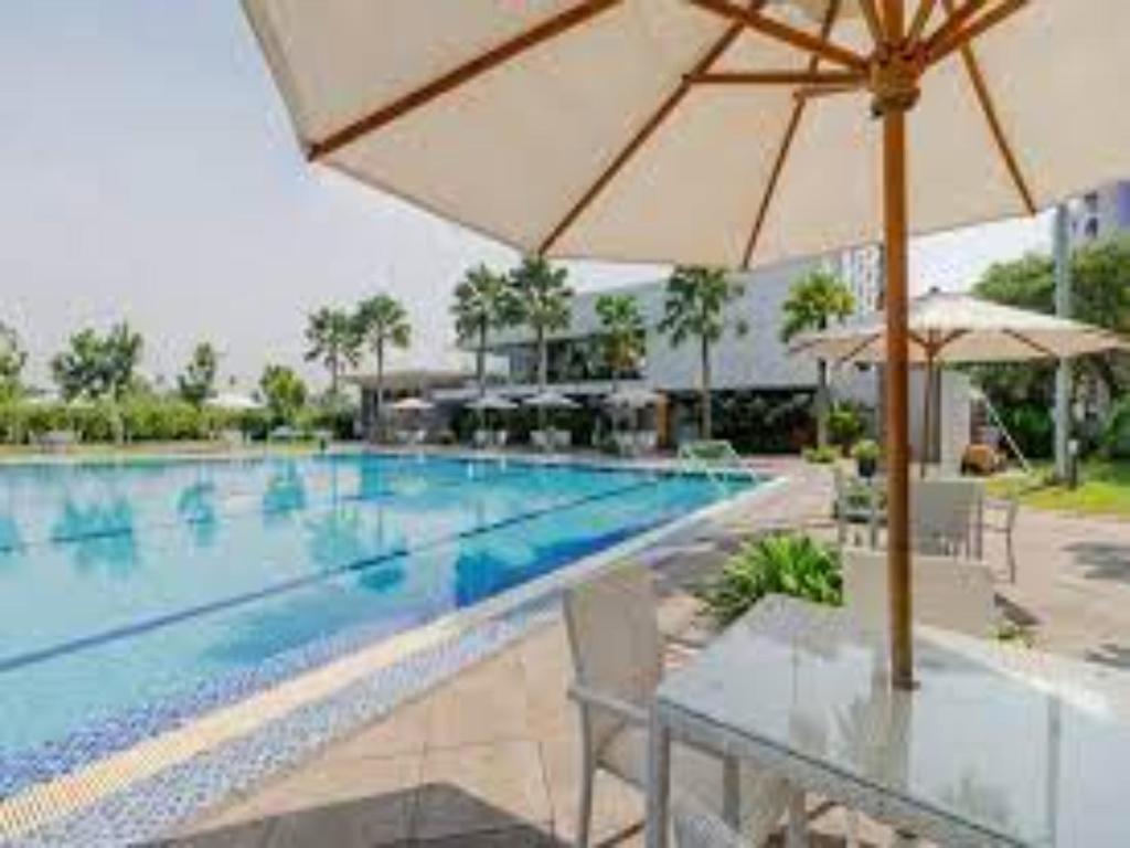 een groot zwembad met een tafel en een parasol bij Aeropolis Near TOD M1 in Teko