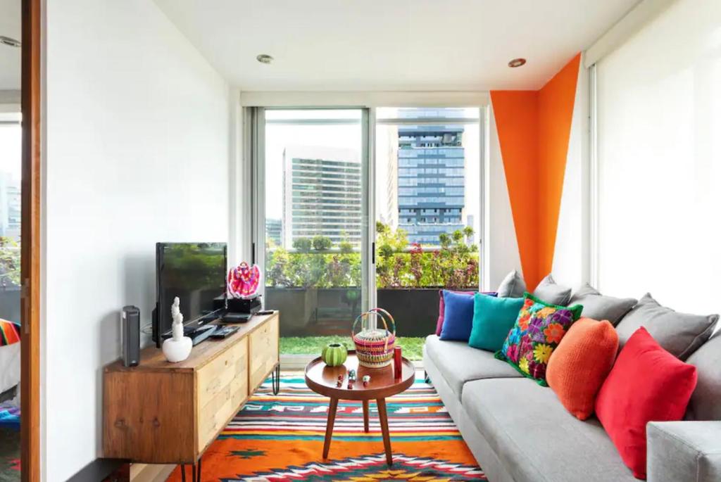 a living room with a couch with colorful pillows at Departamento mexicano en Polanco. Pool - gym - parking in Mexico City