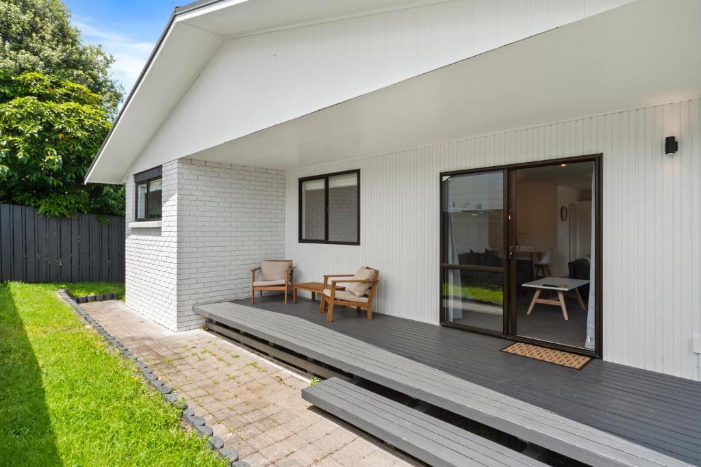 a white house with a deck with a patio at Garden Grove Gem - Lake Taupō Holiday Home in Taupo