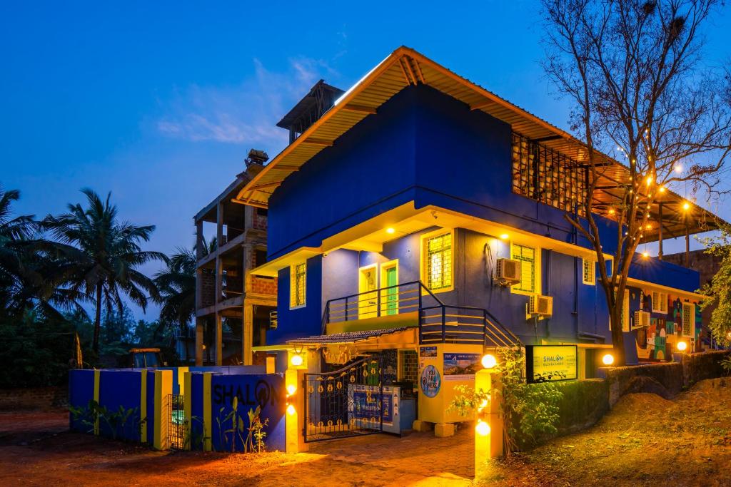 una casa azul con luces delante en Shalom Backpackers Anjuna Goa, en Anjuna