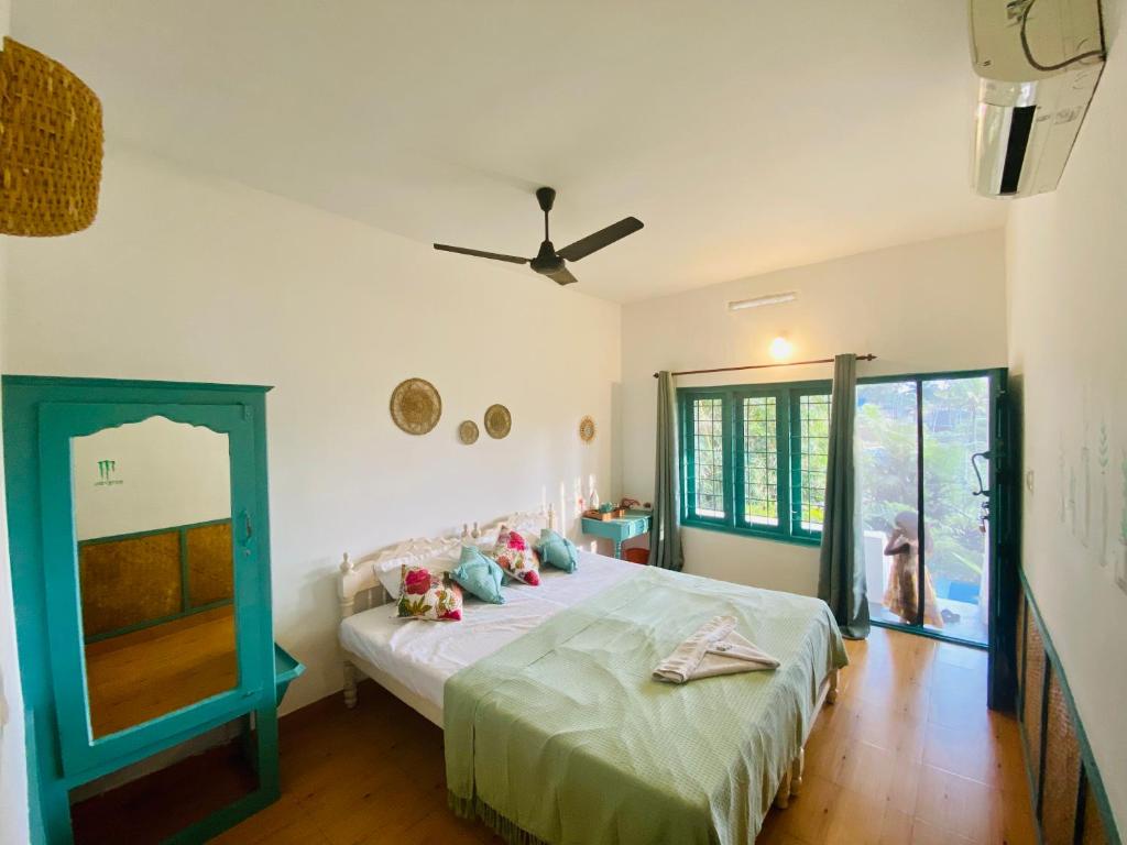 Petit Ana Beach Retreat في فاركَالا: غرفة نوم بسرير ومروحة سقف