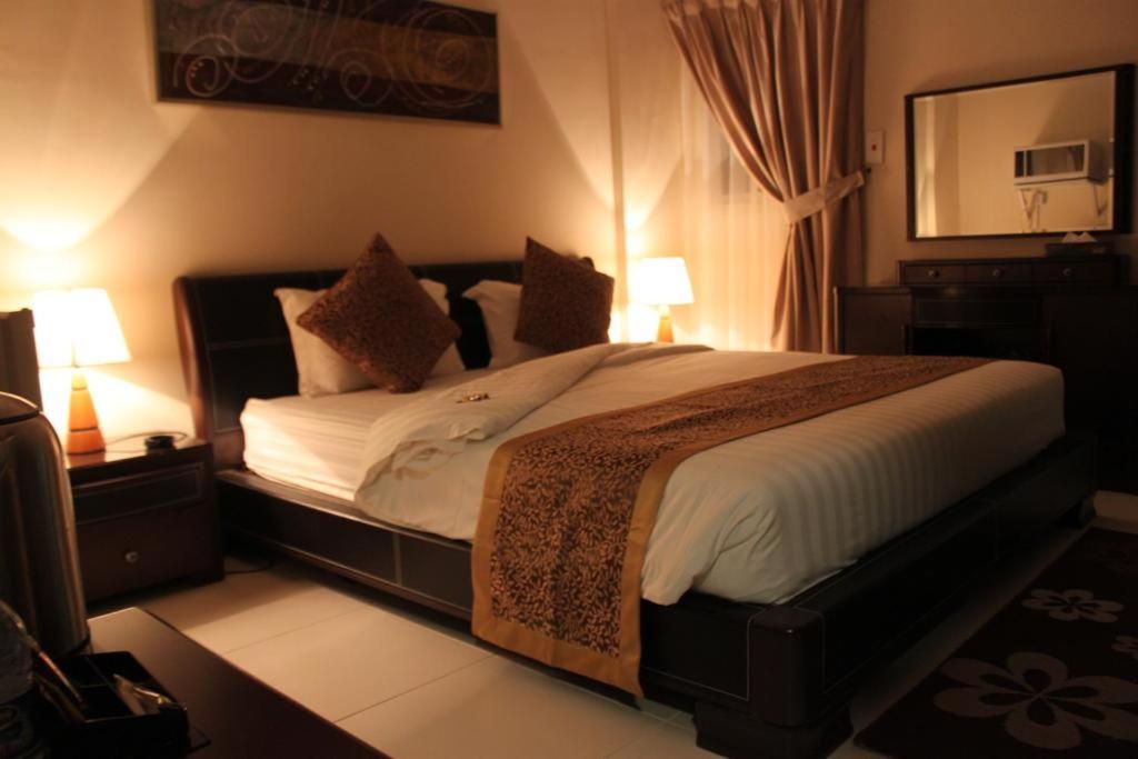 a bedroom with a large bed with two lamps at المواسم الاربعة للاجنحه الفندقية in Al Jubail