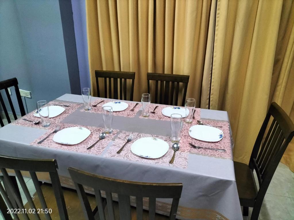a table with plates and wine glasses on it at Yuyu homestay in Johor Bahru