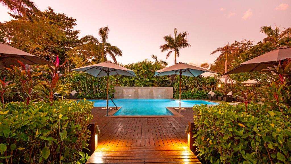 uma piscina com guarda-sóis num deque de madeira em The Billi Resort em Broome