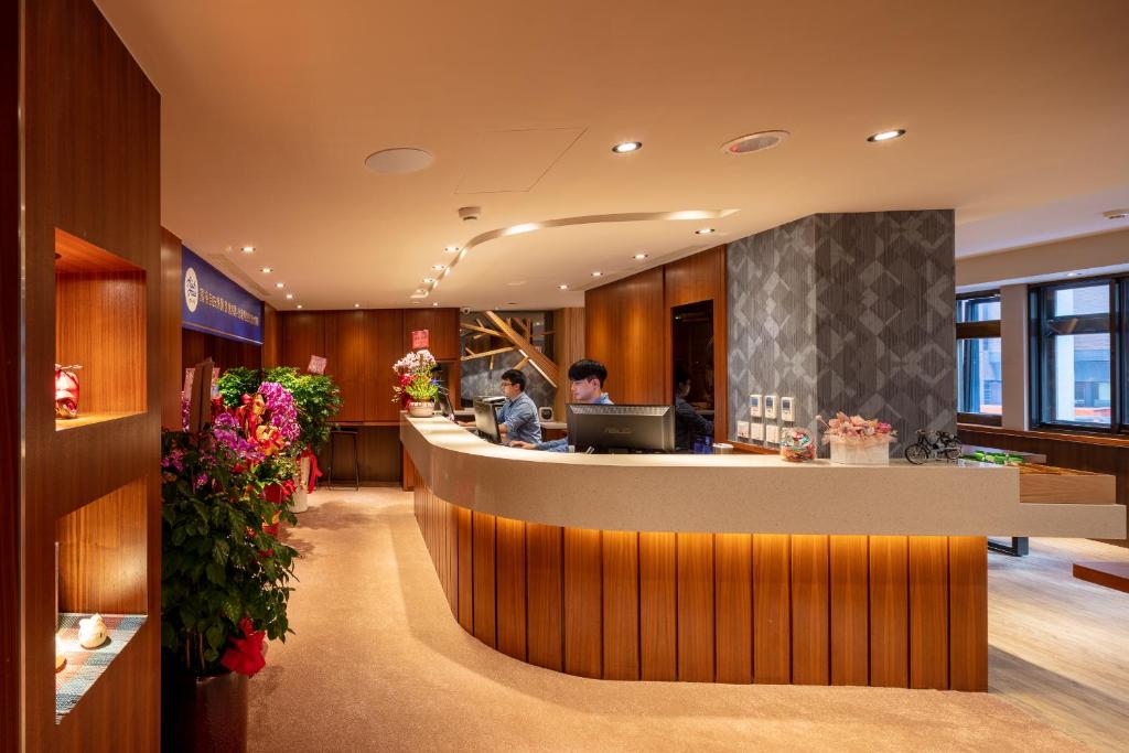 a hotel lobby with a reception counter and flowers at Rich & Free Hotel - Kaifeng 富逸旅趣-北車開封館 in Taipei