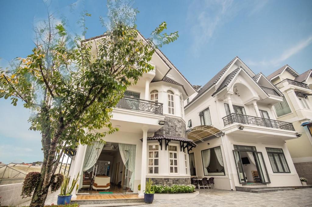 ein großes weißes Haus mit einem Baum davor in der Unterkunft Trung Nghĩa Villa 20 in Da Lat