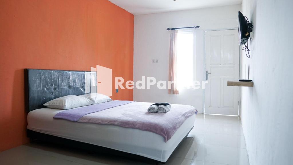 een slaapkamer met een bed met een oranje muur bij El Dhiya Syariah Karawaci RedPartner in Tangerang