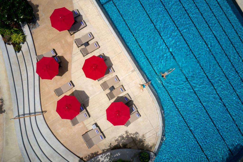 - une vue sur la piscine dotée de parasols rouges dans l'établissement Amari Pattaya, à Pattaya