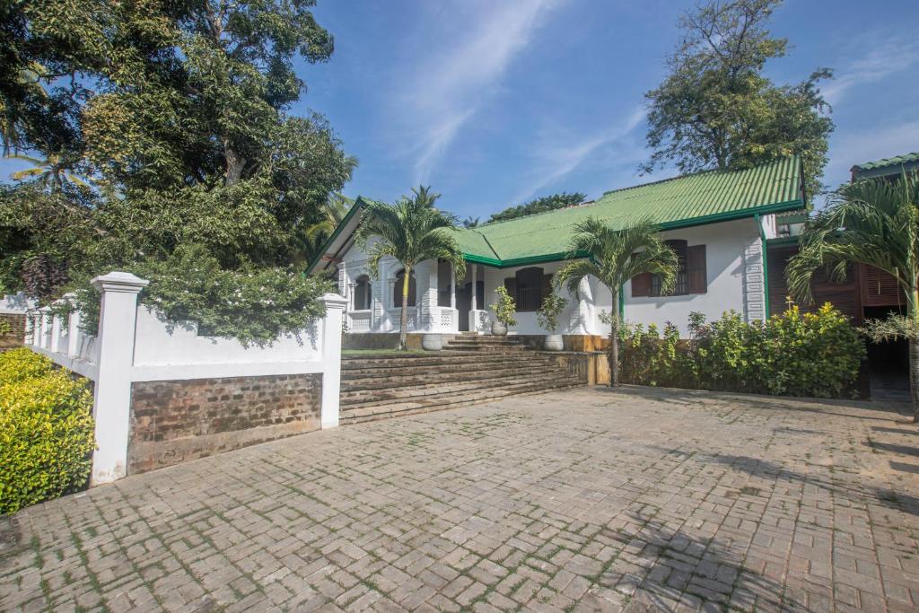 a white house with a green roof and a brick driveway at The Coastal Village Cabanas in Galle