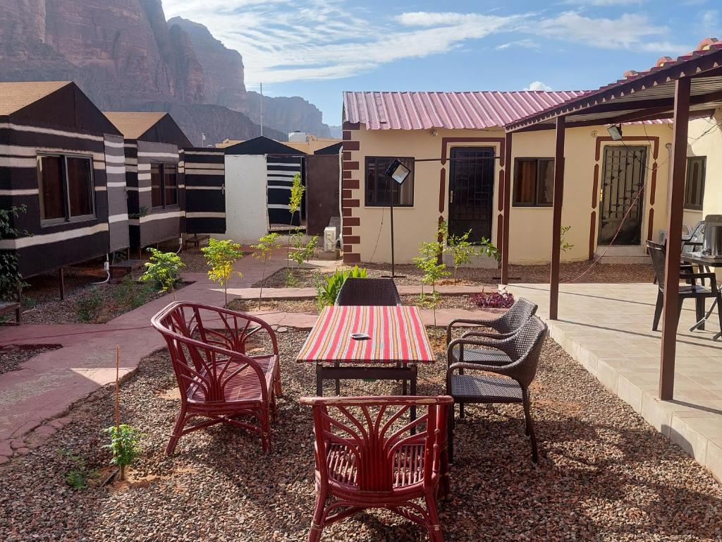 a patio with a table and chairs and a house at Wadi Rum Oryx Hostel & Tours in Wadi Rum