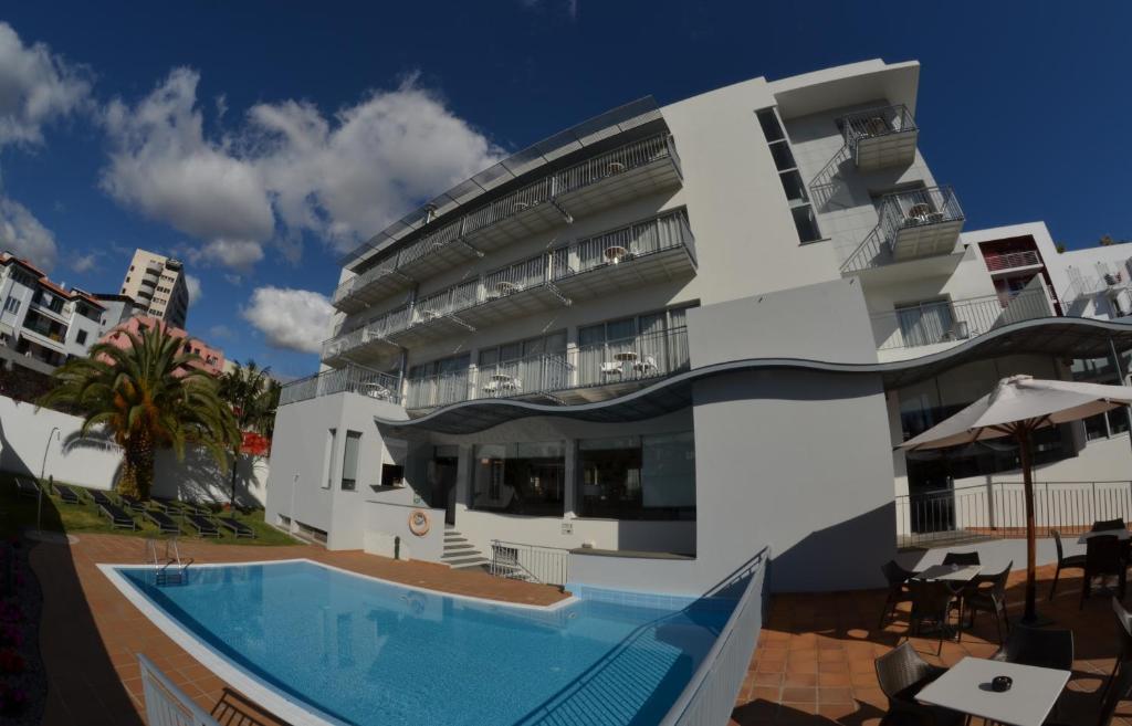 un edificio blanco con una piscina frente a él en Madeira Bright Star by Petit Hotels en Funchal