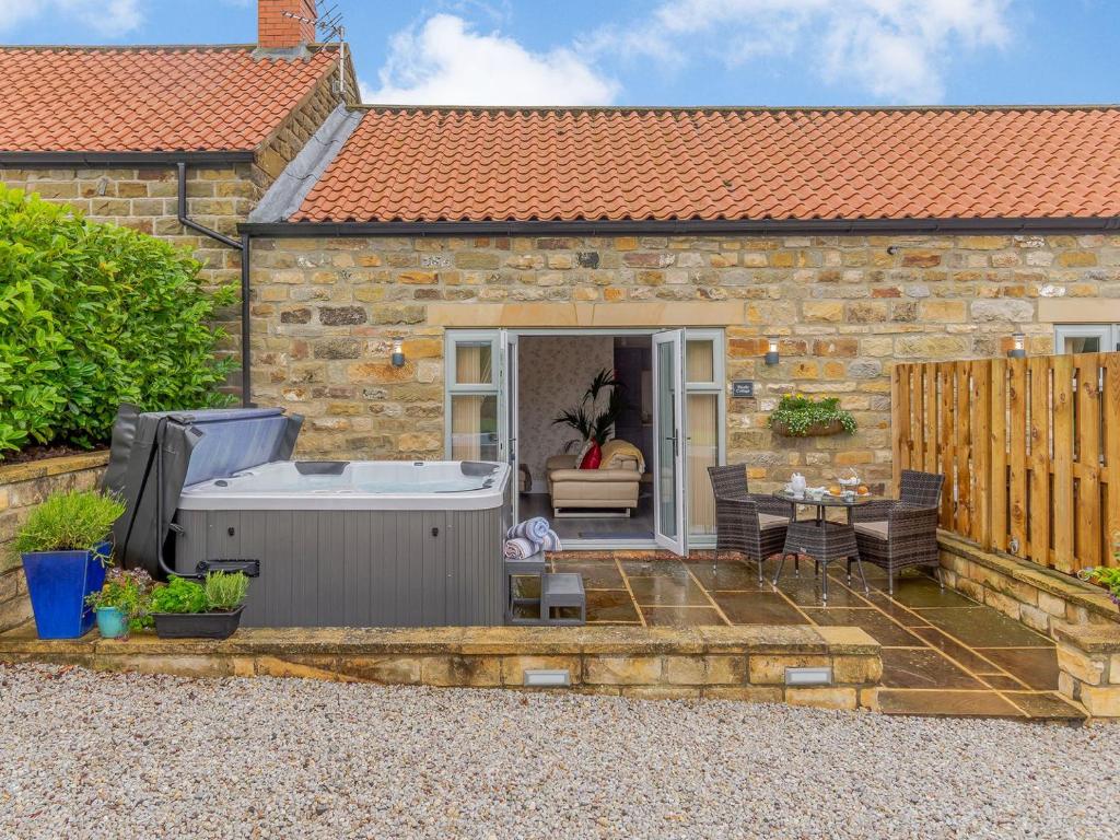 a small stone house with a hot tub and a patio at Thistle Cottage - Uk30523 in Staintondale