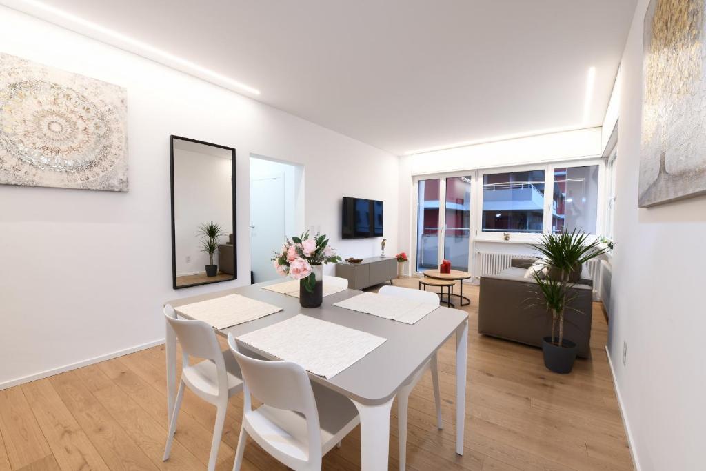 a white dining room with a white table and chairs at Lake Modern Suites - Free Parking in Lugano