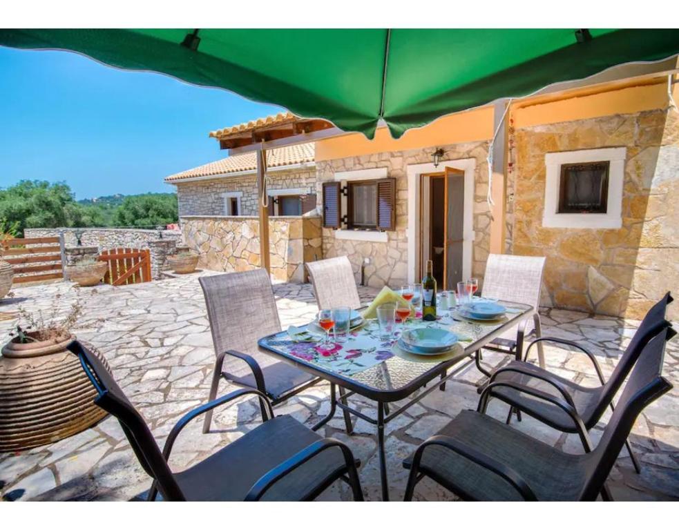 a table with chairs and a green umbrella on a patio at Ria Sweet Home Paxos in Oziás