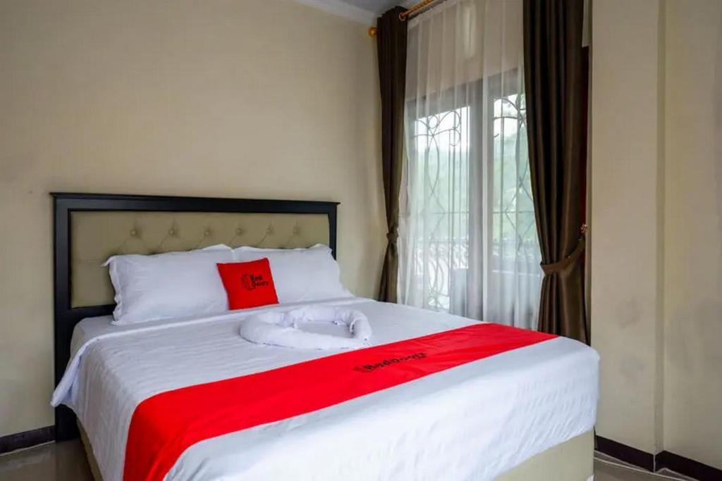 マカレにあるRedDoorz at Makale Tana Torajaのベッドルーム1室(赤いタオル付きのベッド1台付)