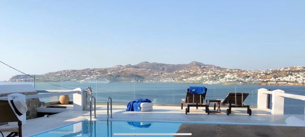 a swimming pool with two chairs and the water at Villa Maestro Mykonos in Agios Ioannis Mykonos