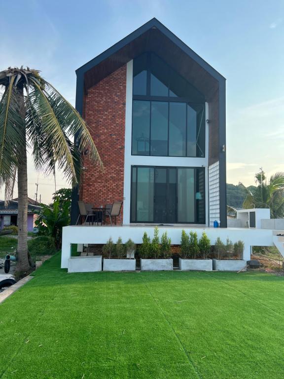 a house with a green lawn in front of it at Talaytime Pool Villa in Laem Sing