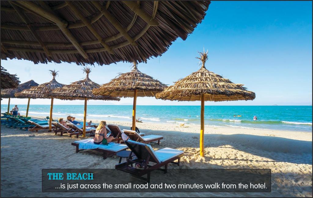 a beach with people sitting in chairs under umbrellas at Fivitel Hoi An Hotel in Hoi An