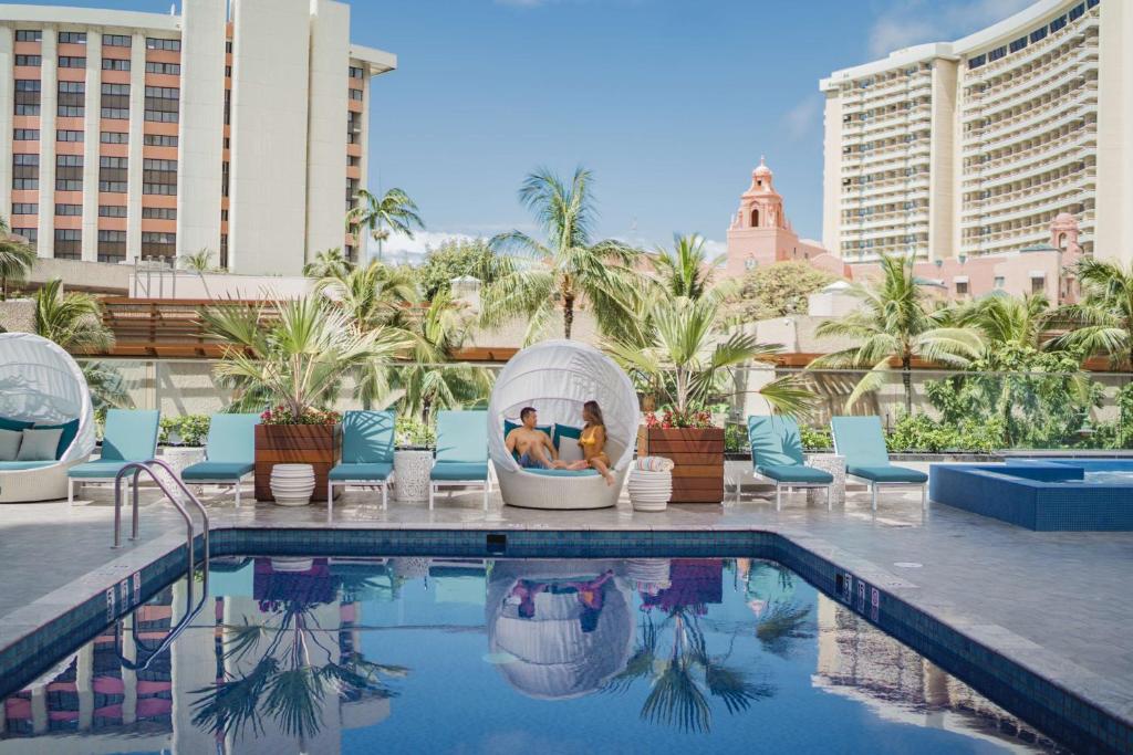 una piscina dell'hotel con due persone sedute in un iguana di OUTRIGGER Waikiki Beachcomber Hotel a Honolulu