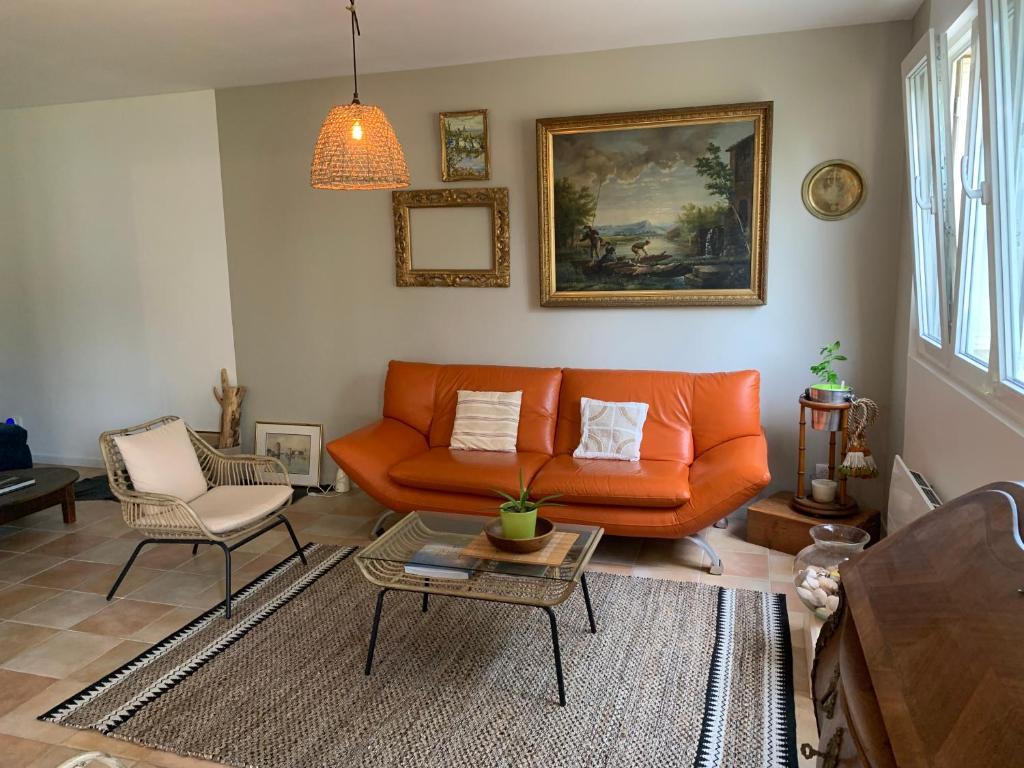 ein Wohnzimmer mit einem orangenen Sofa und einem Tisch in der Unterkunft Bâtisse en pierre XVII siècle 115 M² avec terrasse in Ambarès-et-Lagrave