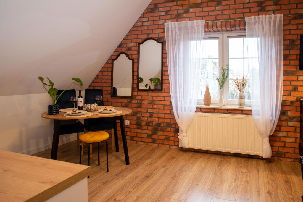 a dining room with a table and a brick wall at Dluga 66 Attic in Gdańsk
