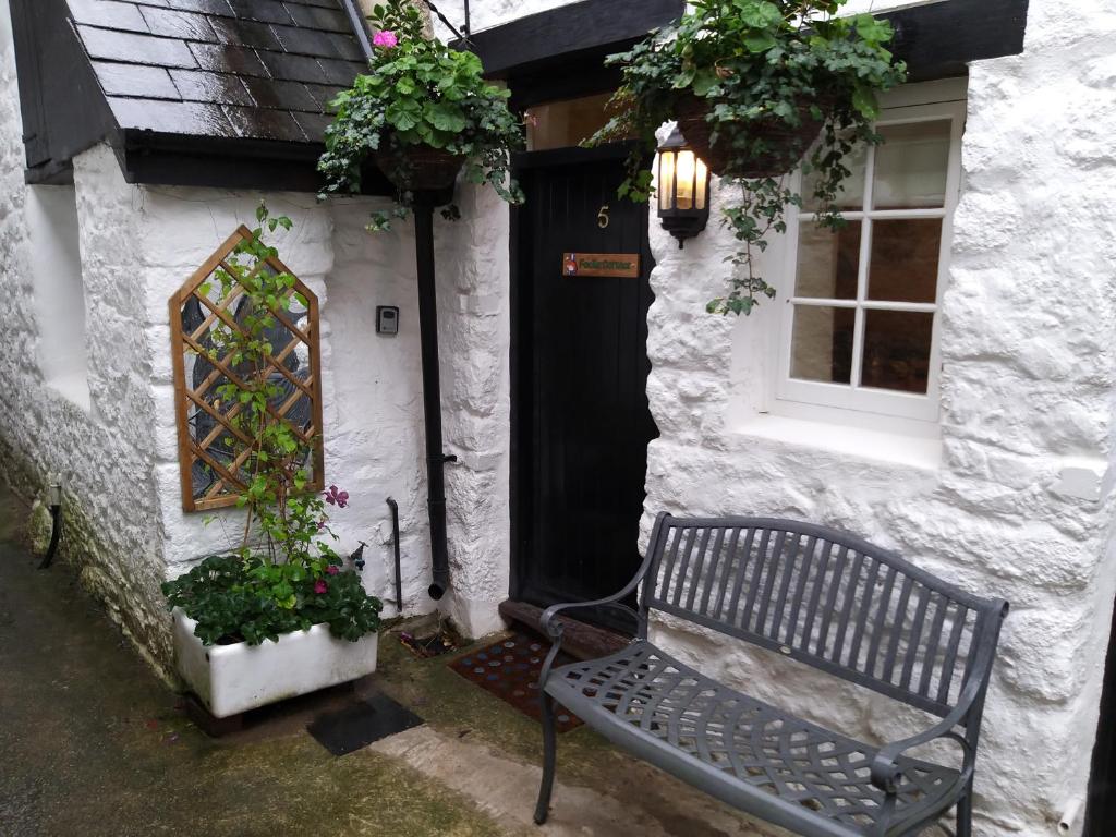 un banco frente a una casa con plantas en Fox Hat Cottage, en Newton Abbot