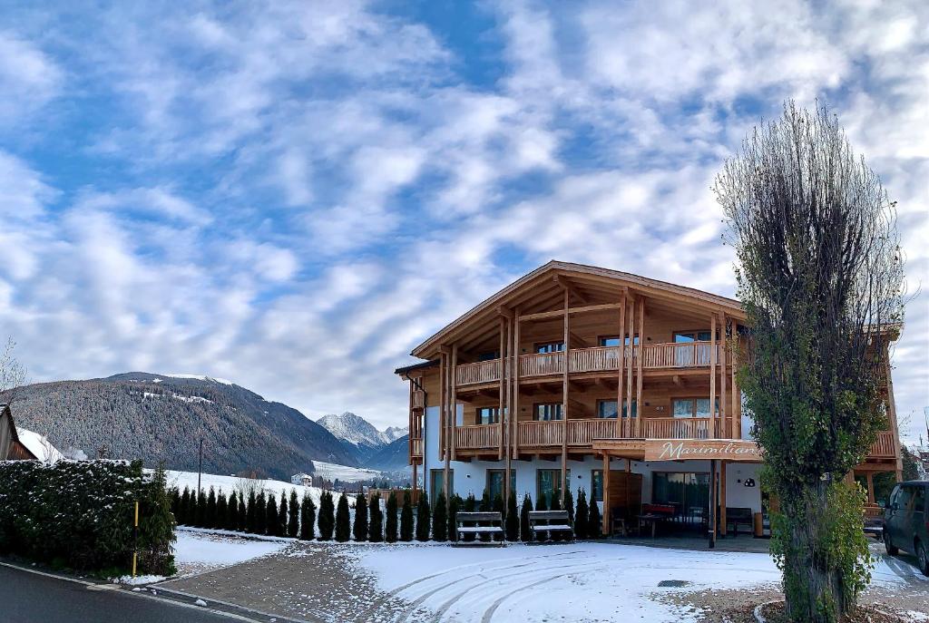 a large wooden building with snow on the ground at Residence Maximilian in Valdaora