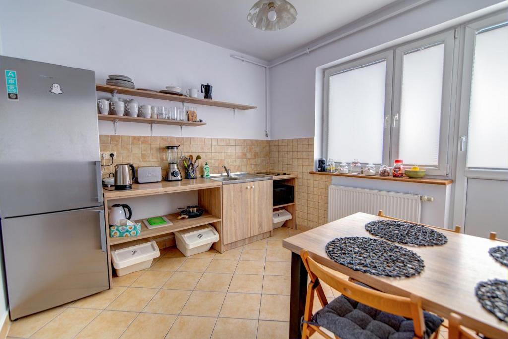 a kitchen with a table and a stainless steel refrigerator at Villa Wesoła pokoje z łazienkami i dostępem do kuchni w centrum Krynicy Zdroju Bezpłatne miejsca postojowe in Krynica Zdrój
