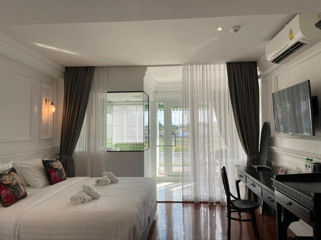 Cette chambre comprend un lit, un bureau et une fenêtre. dans l'établissement Wiang Ville Boutique Hotel, à Chiang Mai